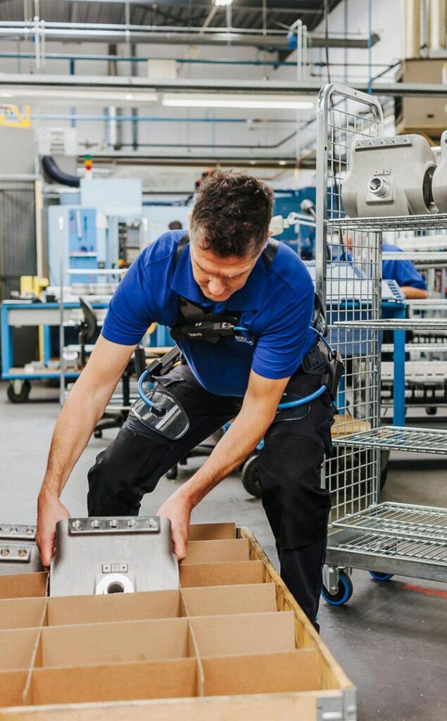 employee using wearable device to lift heavy machinery